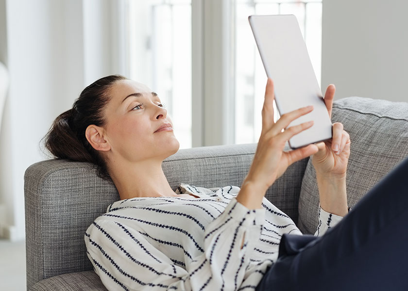 Woman lounging on couch reading tablet