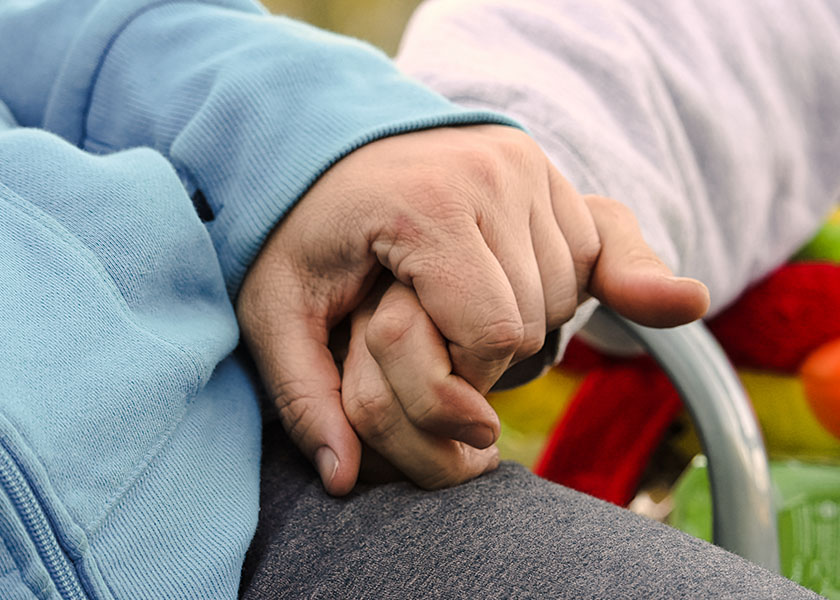 A couple sitting in a chair holding hands. Long-term care planning.